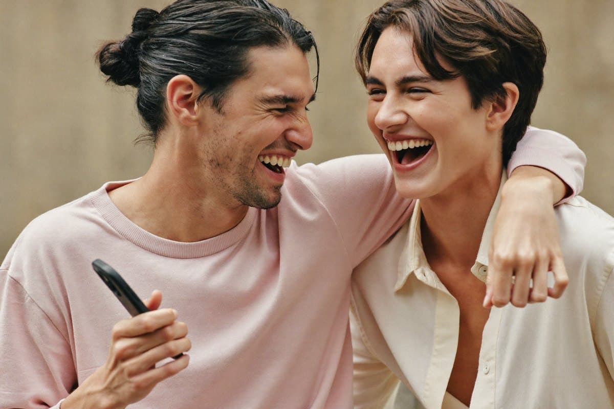 Two friends laughing together, arm around the shoulder