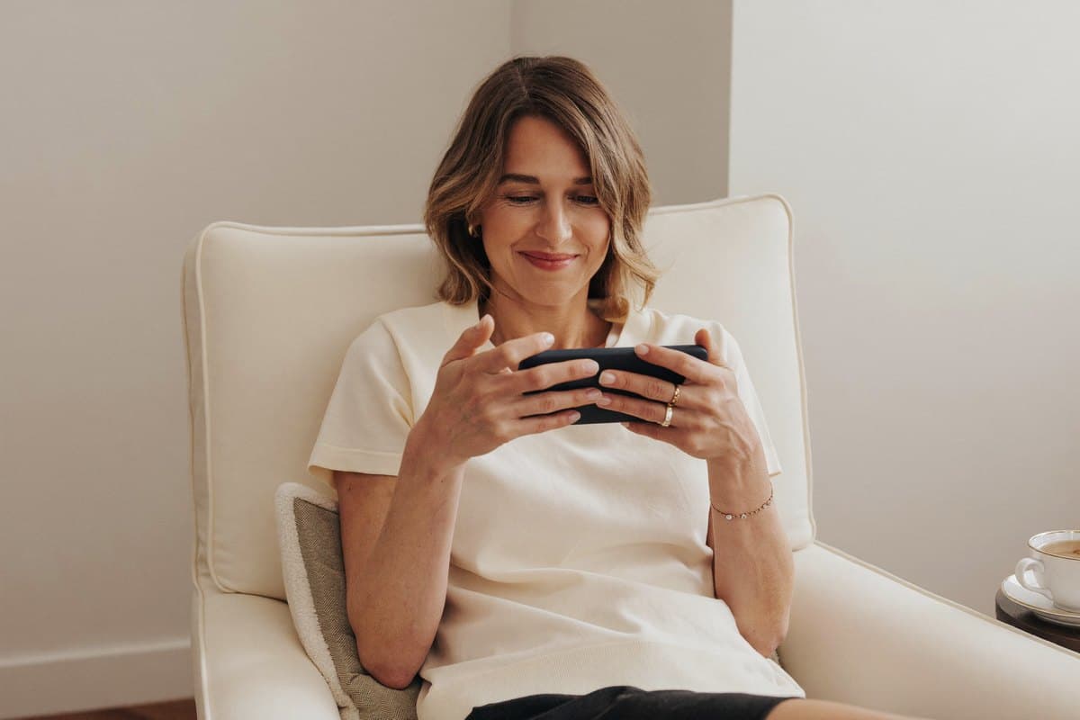 Woman sitting relaxed in her living room, looking content at her phone
